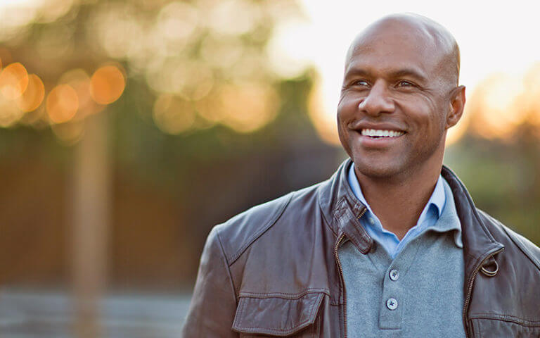 Bald man smiling outside wearing brown leather jacket